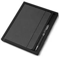 Kit caderno de anotações e caneta. O kit acompanha a caneta, e sua embalagem é presentável. O caderno de anotações é feito de material reciclável que imita a representação do couro, em capa dura com miolo 80 folhas pautadas na cor bege.