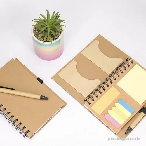 Bloco ecológico personalizado - Um caderno de capa dura em papelão com porta-canetas elástico, encadernação Wire-O e dois bolsos interiores. Contém aproximadamente 70 folhas brancas com pauta além de um bloco com cerca de 20 folhas amarelas autoadesivas. Inclui também seis blocos d