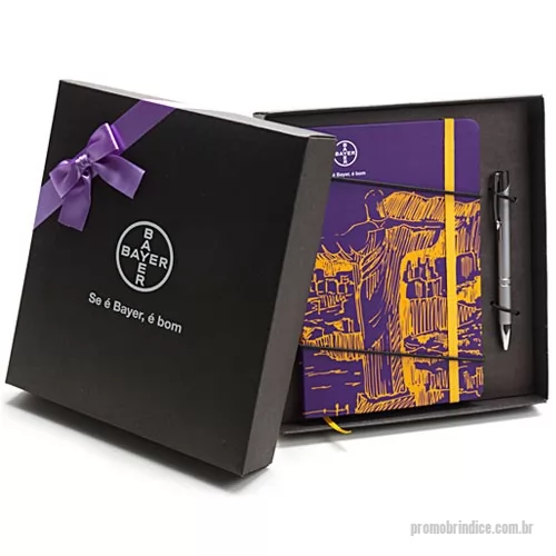 Caderneta personalizada - Kit composto por Bloco de capa dura revestido com couchê 150 g 4x0 cor com laminação fosca frente. Guardas em color plus 180 g 0x0 cor. Miolo sem pauta com 80 folhas em papel polém 70 g 0x0 cor, costurado, cantos arredondados, fechamento com elástico e marcador de cetim. Kit acondicionado em caixa de papel kraft preto 300 g 21 x 23 x 4 cm. A personalização é a 1 cor na tampa da caixa e à laser na caneta metálica. Laço de cetim não incluso, é opcional.