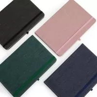 Caderneta com capa dura em linho, fechamento em elástico, marca-páginas em fita de cetim e porta-caneta elástico. Possui cerca de 80 folhas brancas pautadas.
