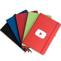 Caderneta tipo moleskine emborrachado com porta caneta elástico em nylon, marcador de página em cetim e fita elástica de nylon para fechar. Contém aproximadamente 80 folhas pardas pautadas.