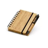 Caderno A6 espiral de capa dura em bambu. Com 140 páginas pautadas de papel reciclado e suporte para esferográfica. Esferográfica em bambu inclusa. A cor e o resultado da impressão nos materiais naturais pode variar entre produtos. 105 x 148 mm