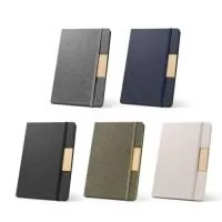 Caderno A5 personalizado com capa dura revestida em tecido rPET 100% reciclado e detalhe em bambu, ideal para brindes corporativos, kits de onboarding, eventos, treinamentos, convenções e presentes empresariais. Possui 160 páginas pautadas em papel 100% reciclado na cor marfim, fita separadora e elástico para fechamento. O acabamento em tecido reciclado e bambu proporciona visual moderno, elegante e sustentável, agregando maior valor percebido ao brinde. Pode ser personalizado com logotipo ou identidade visual da empresa. Excelente opção para clientes, colaboradores e ações de relacionamento. Medidas aproximadas: 14,6 x 21 cm.