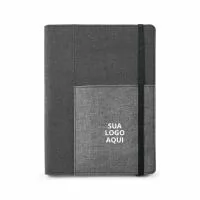 Impressione seus clientes e colaboradores com nossa Capa de Tecido em Poliéster, acompanhada por um caderno A5 removível com 80 folhas lisas. Ideal para anotações diárias, reuniões e planejamento, este produto conta com um bolso interior e suporte para esferográfica (não inclusa), proporcionando praticidade e organização. Fornecida em uma embalagem de non-woven, garante uma apresentação elegante e sustentável. Dimensões: 160 x 220 mm; Bolsa: 205 x 250 mm.  Escolha um brinde que combina funcionalidade, elegância e compromisso com a sustentabilidade. Encante seus clientes e colaboradores com um presente que faz a diferença!