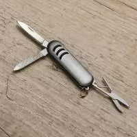 Mini canivete metal 3 funções com detalhes emborrachados preto(três linhas frente e verso). Possui: lixa, lâmina de corte e mini tesoura e acompanha pequena argola para utilizar como chaveiro.