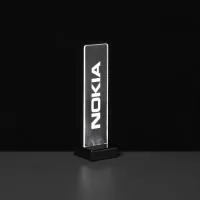O luminoso da Nokia, desenhado para destacar a marca em diversos ambientes como eventos, pontos de venda e escritórios, apresenta o nome da marca gravado em acrílico, que, quando iluminado por LED, garante visibilidade e destaque constantes.  Este display, energizado por uma fonte conectada à tomada, foi criado de acordo com as especificações do cliente, resultando em uma peça exclusiva e personalizada para cada ocasião.  Realce a presença da sua marca com displays luminosos de acrílico da AD Plastic, perfeitos para qualquer ambiente e ocasião.