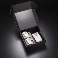 Kit VIP Café apresentado em uma elegante embalagem, perfeito para apreciadores de café. Contém duas canecas de vidro com capacidade de 350ml, proporcionando uma experiência sofisticada ao servir. Acompanha um pacote de café gourmet de 250g, garantindo sabor e qualidade para momentos especiais. Um brinde refinado e exclusivo da Youdu Brindes.