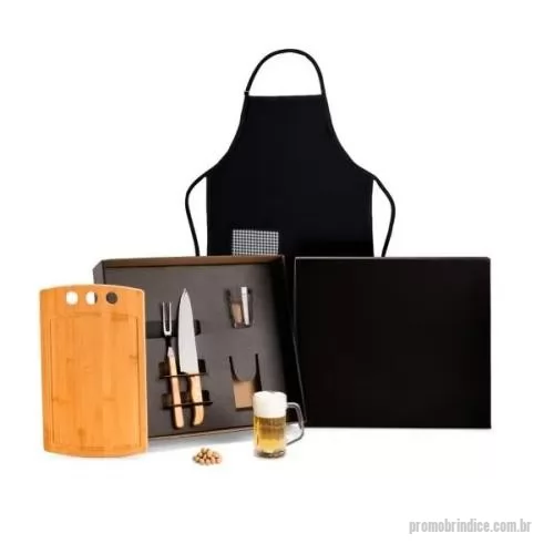 Kit churrasco personalizado - Composto por tábua com três furos em Bambu; garfo trinchante e faca 8'' em Madeira/Inox; avental em Brim preto com um bolso frontal xadrez; copo americano multiuso e caneca americana para cerveja/chopp em vidro.  Download Fotos