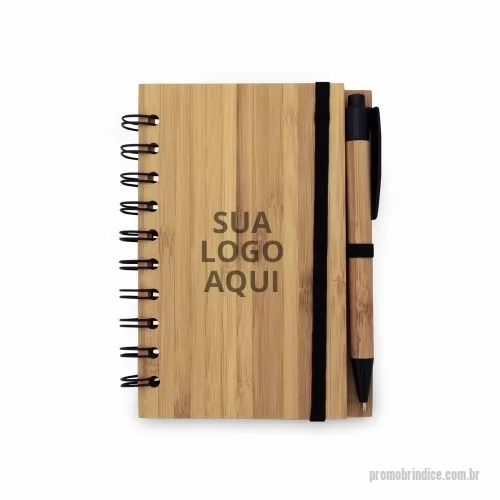 Kit de Caderno e Esferográfica personalizado - Destaque sua marca com o nosso exclusivo Caderno A6 Espiral de Capa Dura em Bambu! Feito com materiais naturais, este caderno possui 70 folhas pautadas de papel reciclado, garantindo uma escolha sustentável e ecológica. Inclui suporte para esferográfica e uma esferográfica em bambu inclusa, tornando-o um brinde completo e sofisticado. Observe que a cor e o resultado da impressão nos materiais naturais podem variar, adicionando um toque único a cada peça. Com dimensões de 105 x 148 mm, é perfeito para o uso diário, seja no trabalho ou em casa.  Escolha um brinde que combina estilo, sustentabilidade e funcionalidade. Encante seus clientes e colaboradores com um presente que faz a diferença!