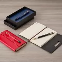 ara quem busca registrar anotações de forma prática e acessível, nosso Kit para Anotações com Caneta é a escolha perfeita. Com aproximadamente 112 folhas amarelas pautadas e feito em couro sintético, o kit vem acompanhado de uma caneta metálica com carga esferográfica preta e um porta-caneta que também serve como fecho para o kit
