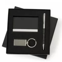 Kit executivo com 3 peças em estojo preto de papelão revestido com espuma interna. Possui: caneta metal prata com detalhes coloridos e quadriculados, clip metal com anel superior na ponta e dois anéis centrais(aciona por giro); porta cartão em couro sintético texturizado com detalhes em metal(detalhes em metal externos espelhados e internos escovados e parte interna com veludo) fecha por imã; chaveiro metal retangular com chapa espelhada(fumê) e parte traseira texturizada.