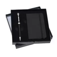 Conjunto executivo 2 peças em estojo de papelão com tampa e parte interna revestida de espuma. Contém: caneta metal preta com anel e detalhes em prata, Livro de anotações em sintético com aproximadamente 80 folhas amarelas com pauta. Acompanha placa metálica para gravação.