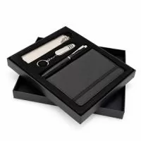 Kit executivo composto por quatro itens: caderneta, caneta, canivete e marcador de página. A caderneta possui capa em poliuretano (PU), elástico para fechamento, marca-página em fita de cetim e aproximadamente 76 folhas marfim pautadas. A caneta metálica conta com tampa e carga esferográfica preta de 0,7mm. O canivete em inox apresenta três funções diferentes: lâmina de corte, lixa de unha e uma mini tesoura. O marcador de páginas metálico dispõe de chapa lisa personalizável nas duas faces. Acompanha caixa em papelão com berço removível em plástico de acabamento aveludado para acomodação dos itens do conjunto.