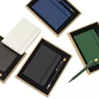 Kit executivo composto por uma caderneta e uma caneta. A caderneta possui capa dura em couro sintético, marca-páginas em fita de cetim e elástico para fechamento, além de aproximadamente 80 folhas com pauta. Por sua vez, a caneta metálica conta com detalhe em bambu, acionamento por clique e carga esferográfica azul de 1,0mm. Acompanha uma caixa de papelão com berço interno em espuma. Gravação da logomarca em 1 cor já inclusa.