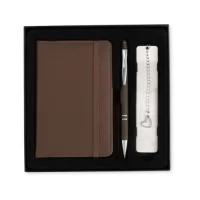 Kit executivo personalizado composto por 3 peças: caderneta, caneta metálica e marcador de páginas. A caderneta possui capa em poliuretano (PU), elástico para fechamento, marca-página em fita de cetim e aproximadamente 76 folhas pautadas na cor marfim. A caneta metálica possui acabamento emborrachado, acionamento por clique, ponteira touch para telas sensíveis ao toque e carga azul de 1,0 mm. O marcador de páginas metálico possui chapa lisa personalizável nas duas faces. Acompanha caixa presenteável em papelão com berço interno de acabamento aveludado. Ideal para brindes corporativos, presentes executivos, kits de onboarding, eventos, convenções, clientes e colaboradores. Pode ser personalizado com logotipo ou identidade visual da empresa.