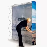 T230 - largura 225cm x altura 225cm - O painel pantográfico é um clássico certo? Porque comprar um novo modelo com a impressão da arte em tecido?  As tecnologias de impressão em tecido atingiram um ponto onde a qualidade da imagem não deve nada as melhores impressões fotográficas. Se por uma lado a qualidade é muito boa, o tecido permite fazer painéis sem emendas, com maior facilidade de montagem e menor peso total para transporte.  No video abaixo você percebe outro ponto muito alto desse modelo. A facilidade e rapidez de montagem. Como em apenas uma maleta que cabe no porta-malas de um carro comum, pode se montar um stand de até 9 metros quadrados em menos de 5 minutos, dispensando os custos de uma equipe de montadores.  As artes dos novos tecido podem ser trocadas sempre que precisar atualizar o seu painel pantográfico