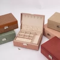 Descrição: Porta-joias em Poliuretano e revestimento interno em tecido aveludado. Apresenta dois compartimentos principais com divisórias em diferentes tamanhos, incluindo uma repartição almofadada com ranhuras. Conta ainda com seis ganchos e um bolso com elástico na parte interna da tampa. O estojo possui trava de segurança e chave para fechamento.  Altura :  9 cm  Profundidade :  17,3 cm  Comprimento :  23,2 cm