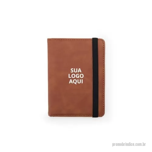 Porta passaporte personalizada - Organize seus documentos com estilo e segurança com o Porta Passaporte em Couro Sintético. Este item essencial oferece proteção RFID, garantindo que os dados dos seus cartões e chips de identificação fiquem seguros contra leituras não autorizadas. Com quatro compartimentos para cartões, três bolsos (sendo um exclusivo para passaporte), espaços para cartões SIM e fechamento em elástico, ele oferece praticidade e organização em um design elegante. Personalize com sua marca e ofereça um brinde sofisticado e útil. Ideal para eventos corporativos e campanhas promocionais, este porta passaporte irá surpreender seus clientes e fortalecer a presença da sua marca.