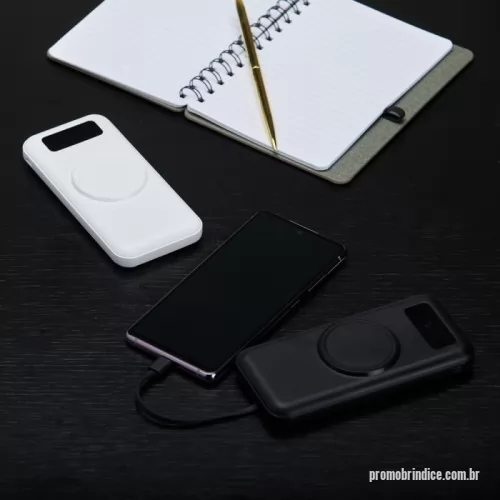 Power bank personalizado -  Carregador portátil com capacidade para até 10.000mAh. Conta com display digital que indica o percentual de bateria do próprio carregador, área para carregamento de dispositivos compatíveis com tecnologia de indução e quatro cabos com saídas micro-USB, USB-C, Lightning e USB-A. Dispõe ainda de entradas micro-USB e USB-C exclusivas para a recarga do próprio carregador.