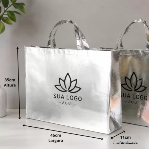 Sacola de TNT metalizado personalizada - Descrição: Sacola TNT metalizada 110g/m² com botão. Confeccionado em TNT com revestimento plástico laminado, parte superior possui botão plástico para fecho.  Altura :  35 cm  Largura :  45,5 cm  Profundidade :  13,5 cm