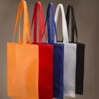 Sacola colorida com alça em material TNT, possui símbolo ecológico/reciclável na costura da alça.